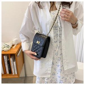 Close-up of a black quilted crossbody bag with a gold twist lock worn by a model
