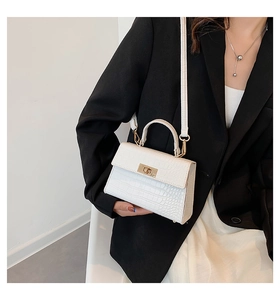 Close-up of a white crocodile texture handbag featuring an elegant golden rotary lock clasp