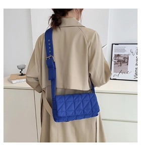 Detail of royal blue quilted handbag featuring glossy lattice texture and wide strap
