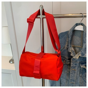 Detail of red cylindrical sporty crossbody bag with wide shoulder strap and waterproof fabric