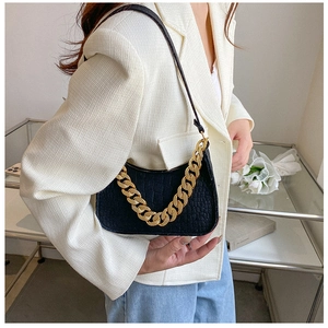 Detail of black faux crocodile leather shoulder bag with decorative chunky gold chain