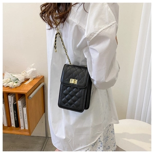 Detail of quilted black shoulder bag with gold twist lock and chain strap on model