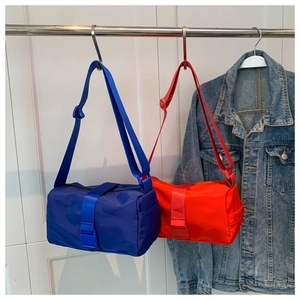 Blue and red nylon cylindrical crossbody bags hanging on a rack with adjustable wide straps