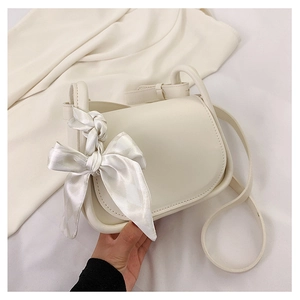 Dettaglio della borsa a tracolla bianco crema con un grande fiocco decorativo in raso