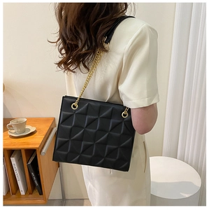 Détail d'un sac bandoulière noir matelassé avec chaîne dorée et anneaux métalliques
