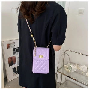 Detail of purple quilted crossbody bag with gold twist lock and chain strap on model