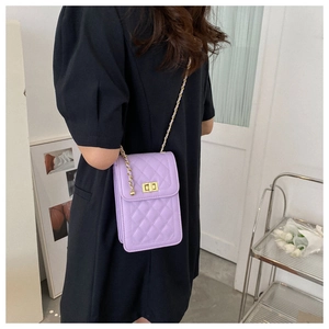 Detail view of a lavender quilted crossbody bag with gold chain strap worn by a model