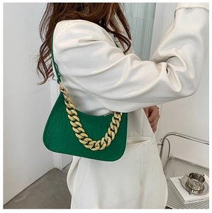 Macro detail of vibrant green faux crocodile leather handbag with thick gold chain