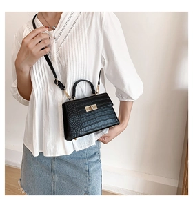 Detail of black crocodile texture bag featuring a vintage gold twist lock and handle