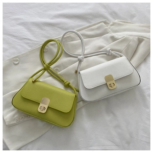 Detail of minimalist baguette bags in green and beige with golden twist locks and knots