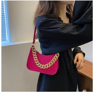 Detail of rose red baguette bag featuring crocodile texture and bold gold chain strap