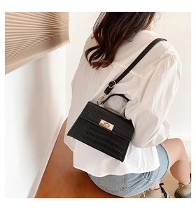 Detail of vintage black crocodile embossed crossbody bag showing texture and golden buckle