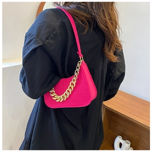 Detail of rose pink crocodile pattern underarm bag with gold chain strap on model