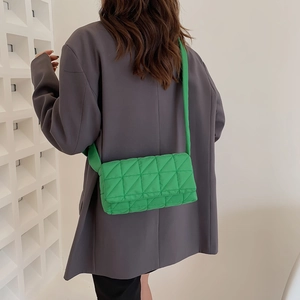 Green quilted nylon crossbody bag with wide strap worn over a grey blazer for women