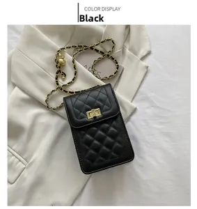 Detail of black quilted PU leather crossbody bag with gold metal lock and chain strap