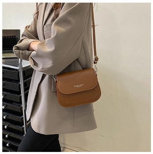 Detail of a brown leather saddle bag with adjustable strap in a modern office setting