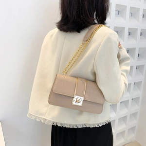 Chic beige crocodile texture underarm bag with gold chain strap on model shoulder