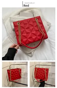 Détail du sac rouge avec gaufrage géométrique 3D et une bandoulière en chaîne dorée
