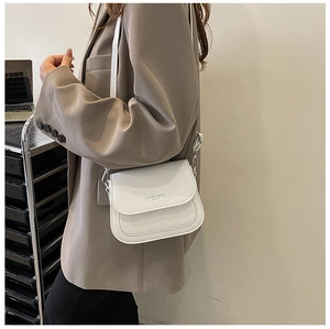 Detail of white leather saddle bag showing diamond quilted pattern and fashion logo