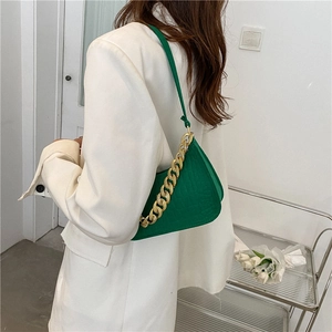 Crocodile pattern green shoulder bag with gold chain strap shown on model shoulder