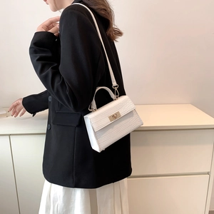 White crocodile pattern crossbody bag with top handle and golden twist lock on model