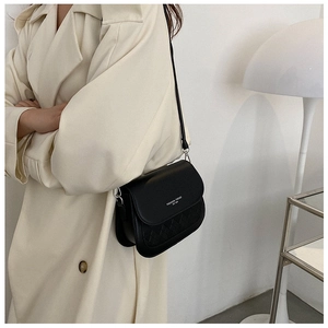 Detailed close-up of a black crossbody bag with woven texture and a stylish logo print