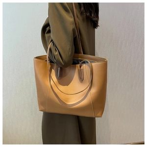 Detail of brown leather tote bag with white contrast stitching and slim shoulder straps