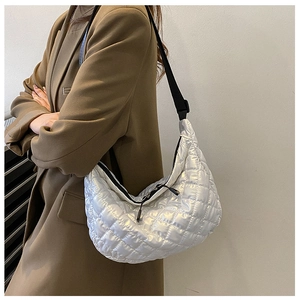 Silver quilted hobo bag with metallic finish and black adjustable strap worn on shoulder