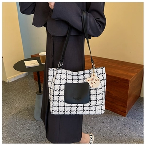 Close-up of houndstooth tote bag with leather pocket detail and cute tiger charm