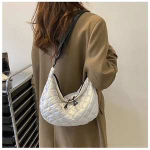 Detailed close-up of a silver quilted hobo bag featuring a crescent shape and metal finish