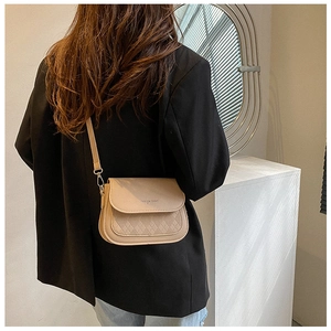 Fashionable beige saddle bag with quilted flap shown on model for size and style
