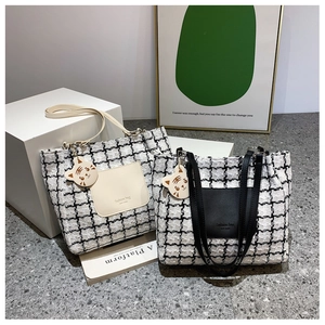 Detail of tweed tote bags with leather trim and tiger pendant on geometric stands