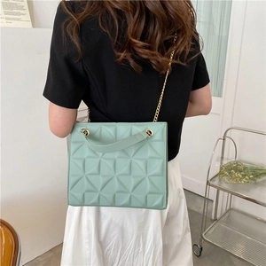 Sac bandoulière matelassé vert menthe avec chaîne dorée porté par un modèle