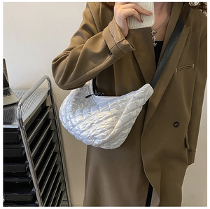 Détail d'un sac bandoulière matelassé blanc en nylon avec sangle noire porté à l'épaule