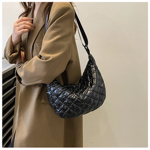 Détail d'un sac demi-lune matelassé noir en nylon avec une large bandoulière réglable