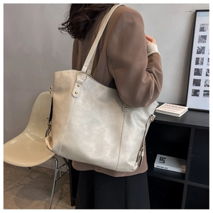 Detail of cream white tote bag featuring natural leather texture and gold hardware ring