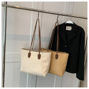 Detail of large minimalist leather tote bags in cream and khaki with long shoulder straps