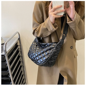 Détail du sac dumpling noir matelassé avec finition brillante et large bandoulière