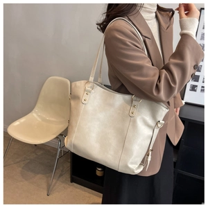 Close-up of cream PU leather tote bag featuring gold ring hardware and dual shoulder straps