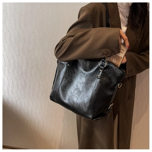 Detail of black oil wax leather tote bag with gold ring hardware shown on a shoulder