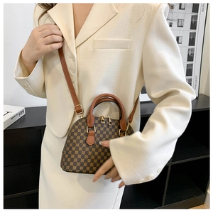 Detail shot of a geometric shell bag worn with a beige suit for a chic commuter look