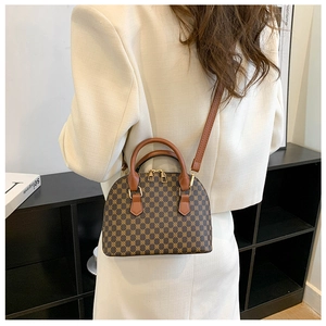 Model view showing the compact vintage pattern shell bag with leather strap and top handles