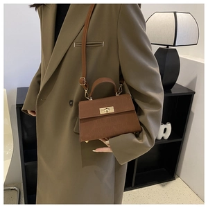 Dettaglio borsa a tracolla marrone con chiusura in metallo dorato e manico elegante