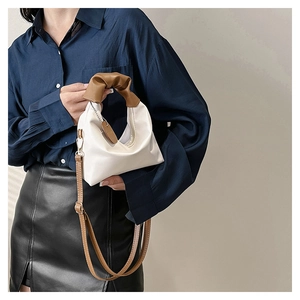 Chic white mini handbag featuring a unique brown ruched handle and detachable shoulder strap