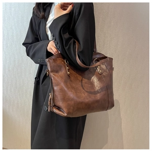 Close-up of retro brown tote bag with oil wax leather texture and gold rivet hardware