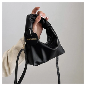 Detail of a black pleated cloud bag with a gold buckle and adjustable shoulder strap