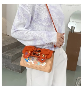 Détail du mini sac bandoulière avec graffitis colorés et bandoulière en cuir orange