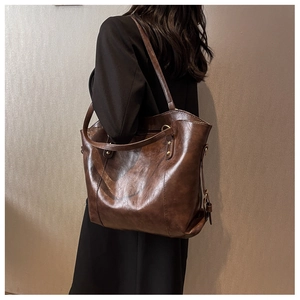 Detail of vintage brown shoulder bag with oily texture and gold hardware on model