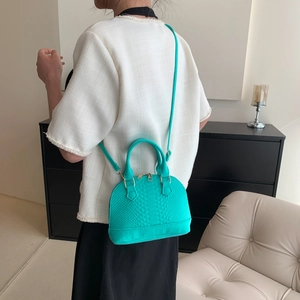 Turquoise shell handbag with diamond quilted pattern shown from a back-wearing perspective