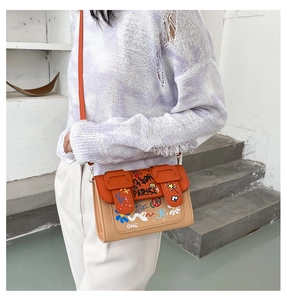 Détail d'un mini sac à bandoulière avec imprimés graffiti et rabat orange vif